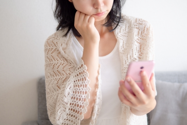 スマホを見て悩む女性